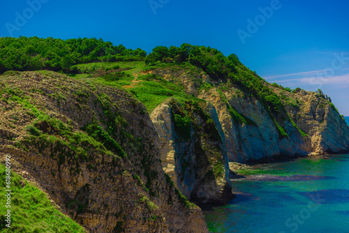 Rocks with green grass by sea on summer sunny day
