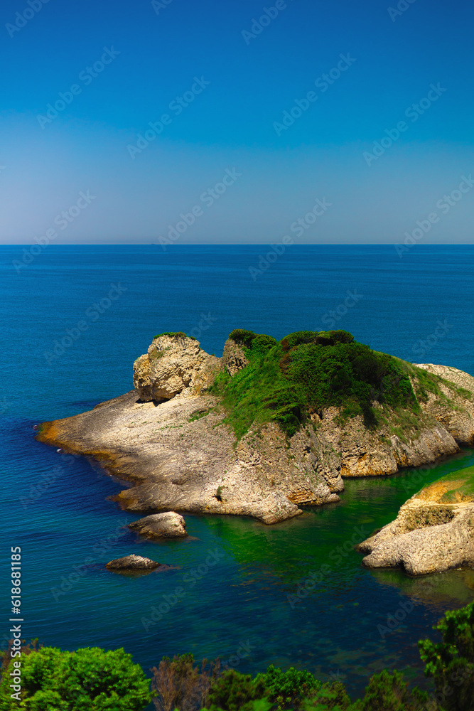 Naklejka premium Green rocky island in sea on summer sunny day