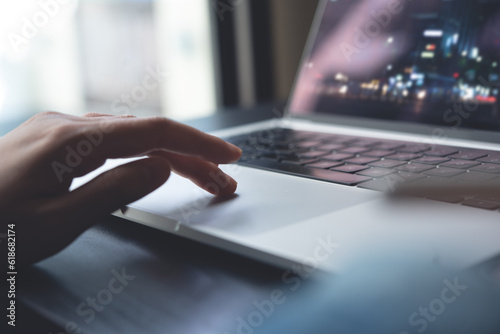 Close up of woman hands searching the information on laptop computer and surfing the internet on office desk, online working, telecommuting, remote work concept photo
