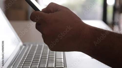 Businessman's hand with financial charts and mobile phone over a laptop on the table