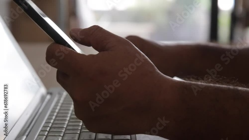 Businessman's hand with financial charts and mobile phone over a laptop on the table