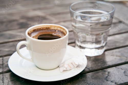 Small cap of strong coffee espresso with glass of clean water on wooden table. High quality photo