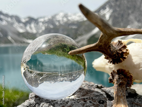 Roebuck antlers next to Lensball, crystal ball, with reflections of Lake Lunersee (Lünersee, Montafon, Vorarlberg). In the background the famous high mountains of austria and switzerland (Rätikon). photo