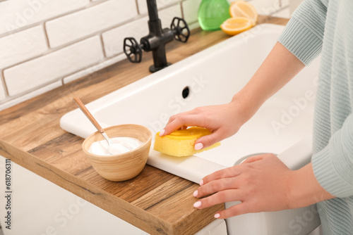Quadro em tela Woman cleaning white sink with sponge and baking soda