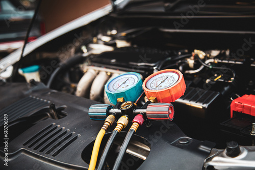 Car care maintenance and service, Hand technician auto mechanic using measuring manifold gauge check refrigerant and filling car air conditioner to fix repairing heat conditioning system. photo