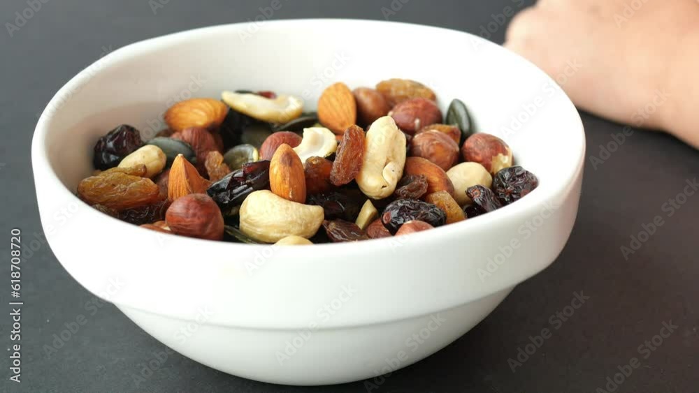 child hand pick nuts from a mixed nut bowl on table child hand pick nuts from a mixed nut bowl on table