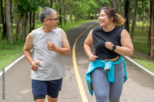 Happy middle age man and young overweight woman enjoy talking to each other during their morning run at running track of a local park