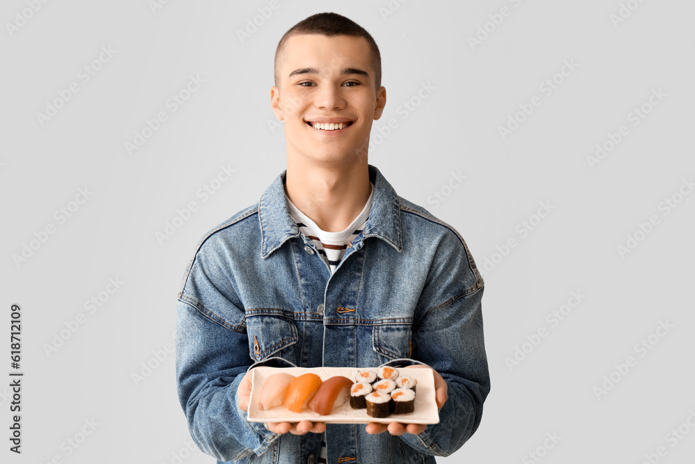 Young man with tasty sushi on light background Young man with tasty sushi on light background