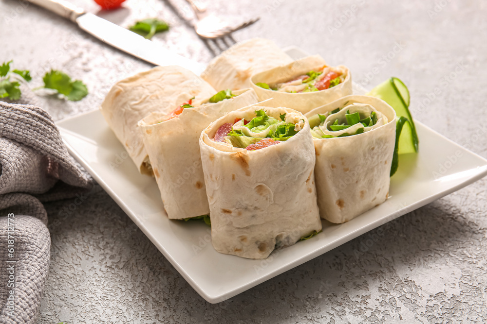 Plate of tasty lavash rolls with vegetables on grey background Plate of tasty lavash rolls with vegetables on grey background