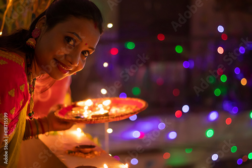 Beautiful Indian woman placing diya with smiling at home on 