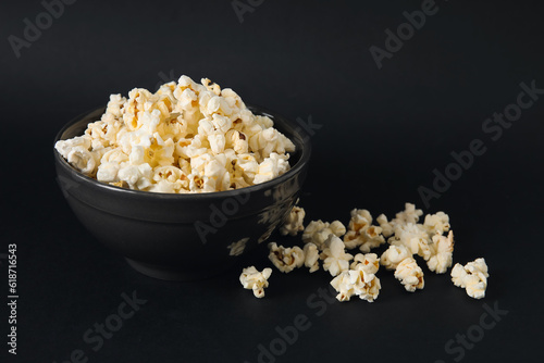 Bowl with tasty popcorn on black background
