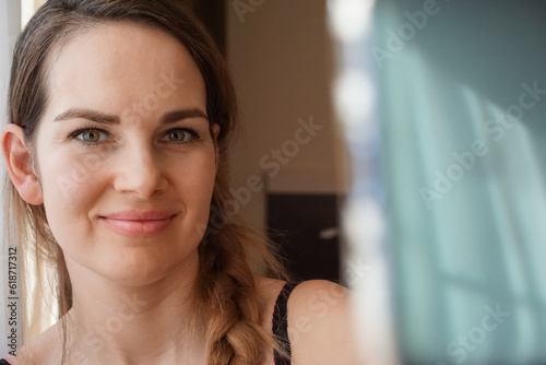 A pretty 35 year old woman without make-up taking a self-portrait with her smartphone. Natural grain on the photo.