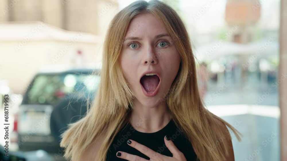 Young blonde woman standing with surprise expression at street