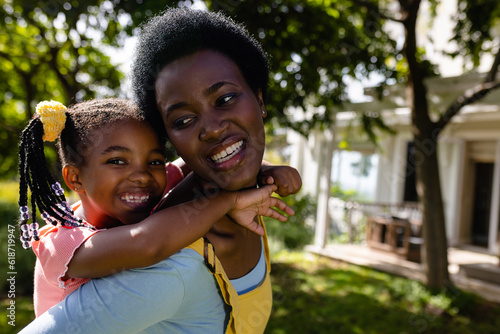 Close-up of african american cheerful mother piggybacking daughter while standing in backyard © WavebreakMediaMicro