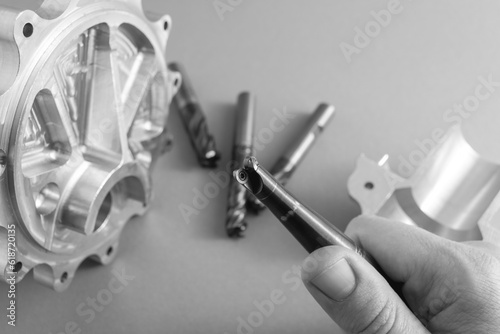 Wallpaper Mural hand holds a milling cutter for metal processing. worn cutter inserts. carbide tool. parts made with this tool lie next to each other. black and white image. Torontodigital.ca