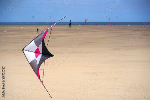Close up of colorful stunt kite  Stabdrachen  on busy sand beach in Holland. Toy for windy days. Recreational sportsmen on the sea.