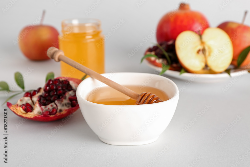 Bowl of honey, pomegranate and apples for Rosh Hashanah celebration (Jewish New Year) on white background