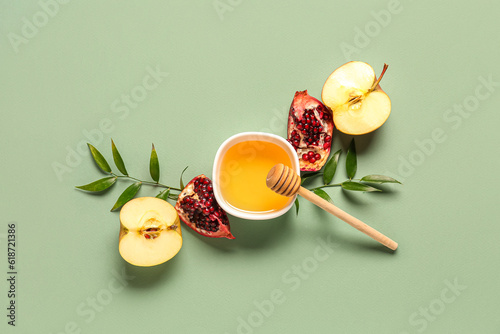 Bowl of honey, pomegranate and apple for Rosh Hashanah celebration (Jewish New Year) on green background