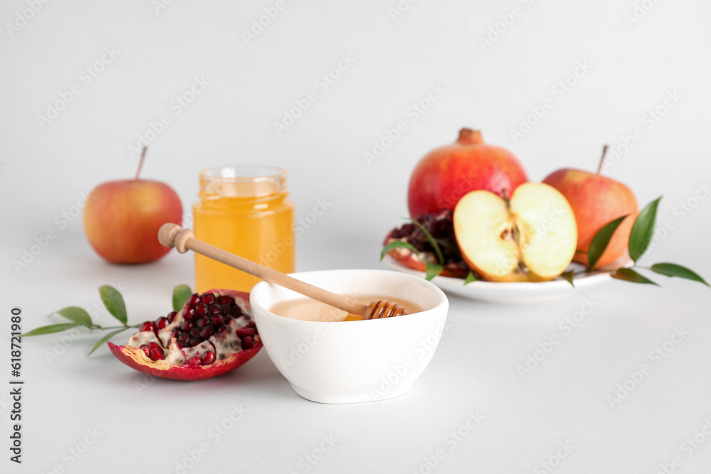 Bowl of honey, pomegranate and apples for Rosh Hashanah celebration (Jewish New Year) on white background Bowl of honey, pomegranate and apples for Rosh Hashanah celebration (Jewish New Year) on white background