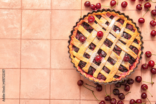 Baking dish with tasty cherry pie on pink tile background