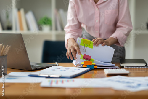 Asian businesswoman working in piles of paper files Documents in the meeting to search and review the various work folders at the desk to record information. management concept