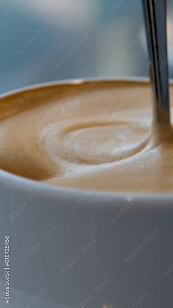 very appetizing coffee foam with spoon quickly stir it in white cup background for any advertising screen saver for music latte coffee with milk 