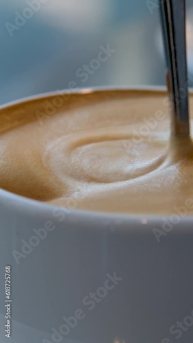 very appetizing coffee foam with spoon quickly stir it in white cup background for any advertising screen saver for music latte coffee with milk 