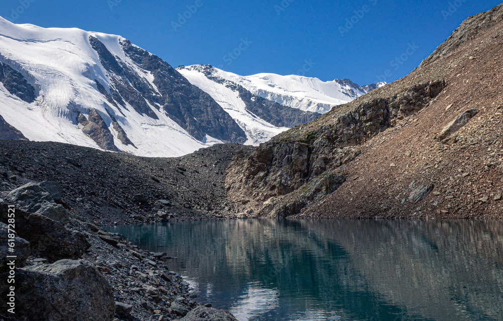 small turquoise lake and hight snowy peaks in the Altai mountains, Aktru at summer day, blue sky