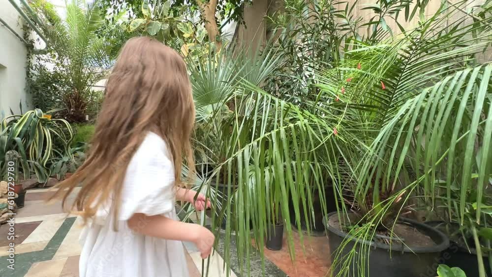 Little blonde girl in the botanical garden. a girl in a white dress ...