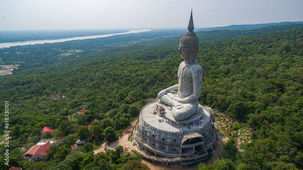 Obraz premium .aerial view Big white buddha statue on mountain for thai people travel visit and respect .praying at Wat Roi Phra Phutthabat Phu Manorom on May 15, 2017 in Mukdahan, Thailand. Kong river background..