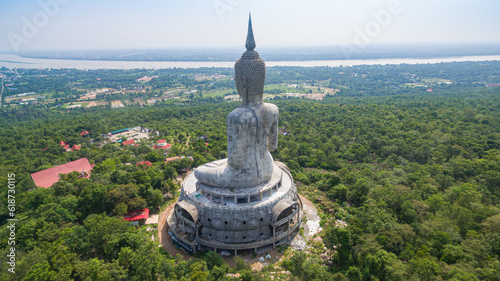 .aerial view Big white buddha statue on mountain for thai people travel visit and respect .praying at Wat Roi Phra Phutthabat Phu Manorom on May 15, 2017 in Mukdahan, Thailand. Kong river background.. photo