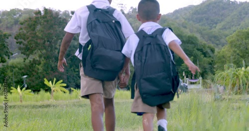Slow motion : Asian children in white primary school uniform with backpacks which are the sons of poor farmers in rural areas going to the school which had to pass through the fields.