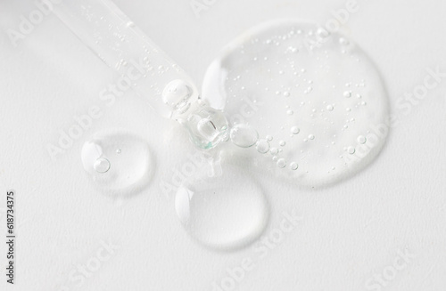 Dropper pipette with trasparent liguid on white background .Cosmetic product, science and research concept