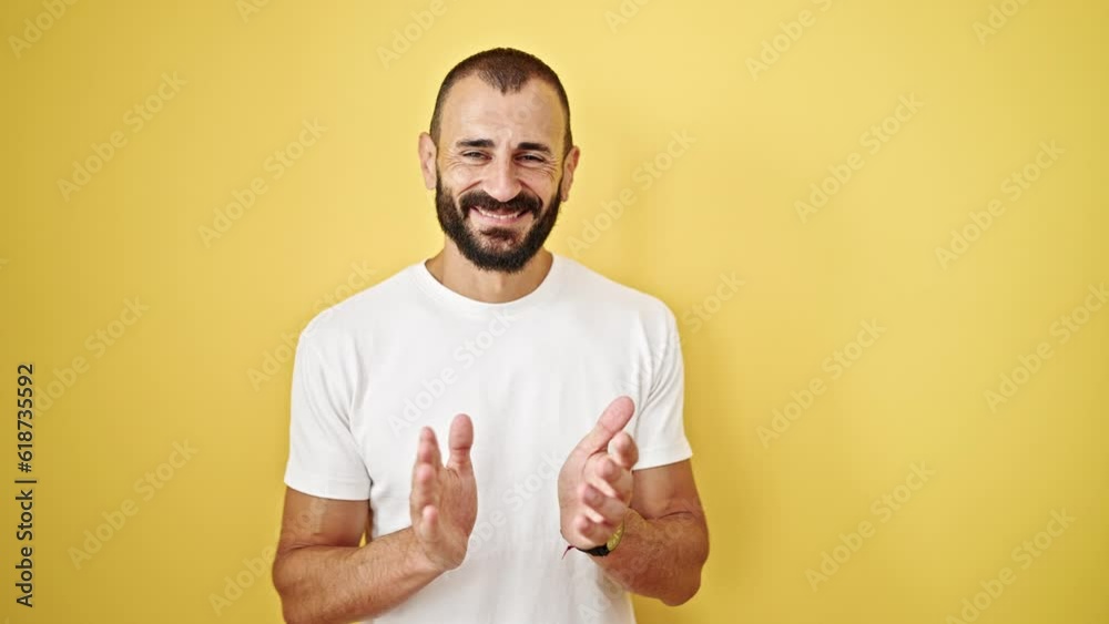 Young hispanic man smiling confident clapping over isolated yellow background Young hispanic man smiling confident clapping over isolated yellow background
