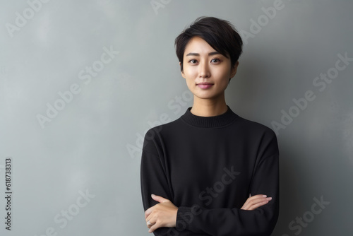Generative AI - Serene Reflections: Thoughtful Asian Woman Smiling, Standing with Crossed Arms, Embracing Minimalist Elegance