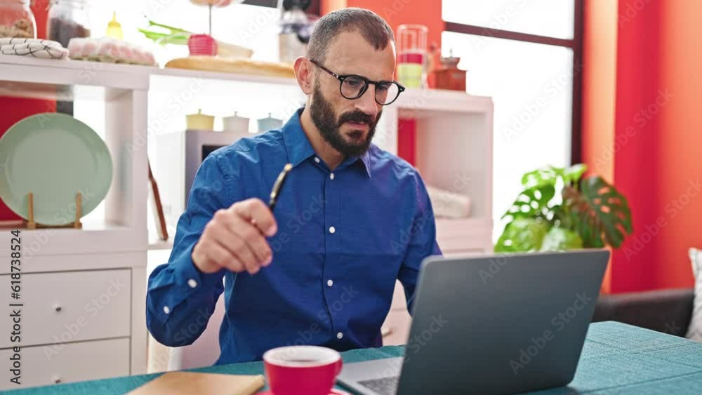 Young hispanic man using laptop thinking at dinning room Young hispanic man using laptop thinking at dinning room