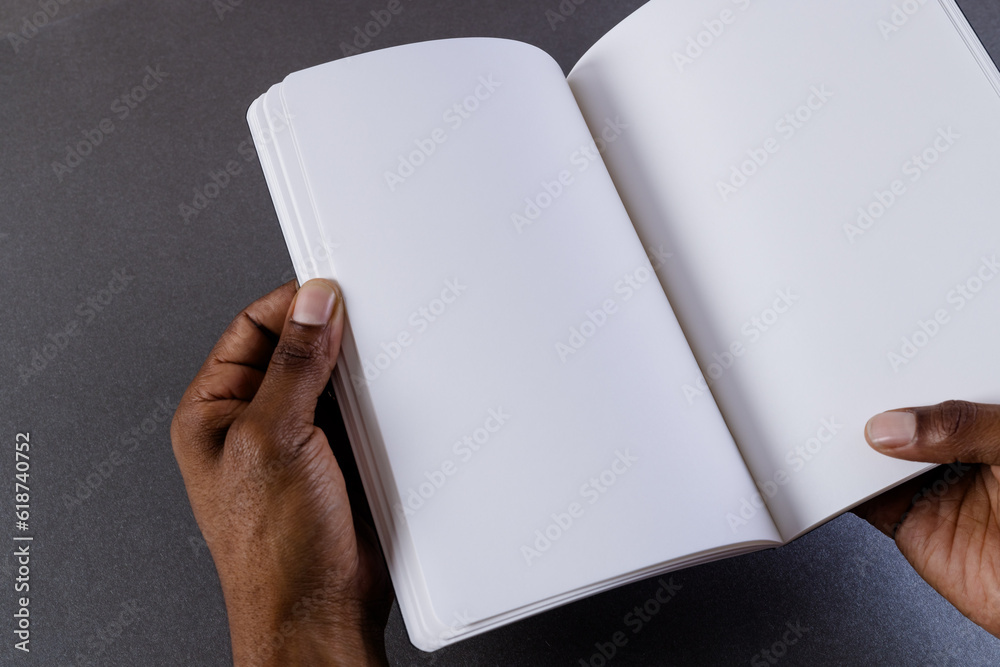 Hands of biracial man holding book with copy space on grey background Hands of biracial man holding book with copy space on grey background