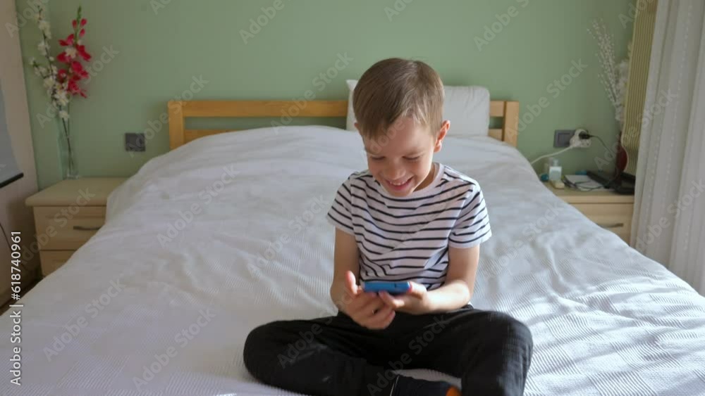Little boy using smartphone sitting on a bed in the morning. 4k slow motion video footage