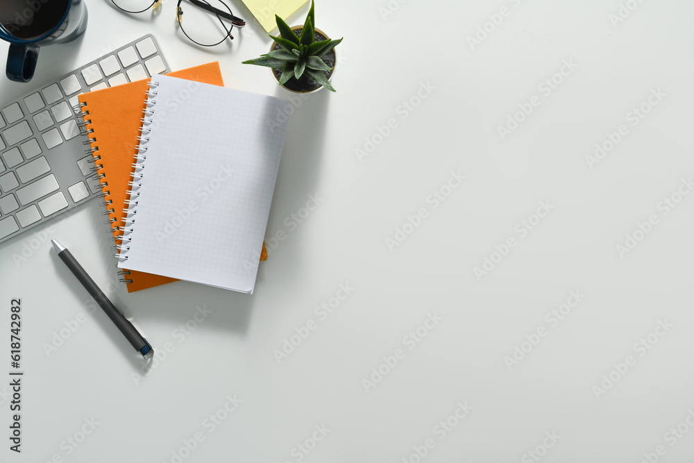 Top view blank notepad, glasses, coffee cup and keyboard on white office. Copy space for your text