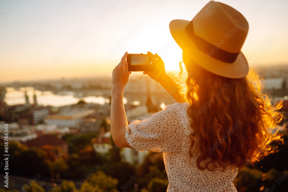 Tourist woman shoots a city landscape at dawn on a smartphone. Travel in Europe. Lifestyle, travel, tourism, nature, active life, blogging.
