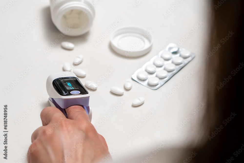 Woman using finger pulse oximeter, healthcare monitoring concept. Woman using finger pulse oximeter, healthcare monitoring concept.