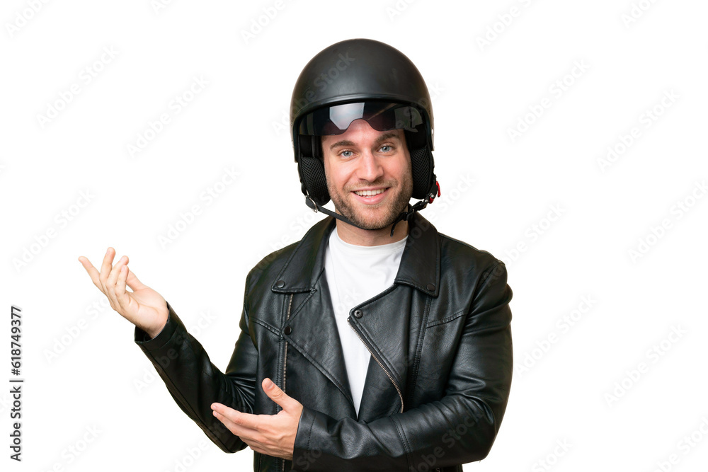 Young caucasian man with a motorcycle helmet isolated on green chroma background extending hands to the side for inviting to come Young caucasian man with a motorcycle helmet isolated on green chroma background extending hands to the side for inviting to come