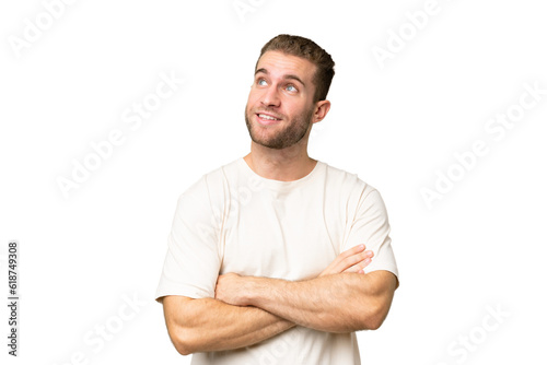 Young handsome caucasian man isolated on green chroma background looking up while smiling