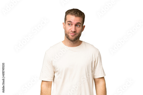 Young handsome caucasian man isolated on green chroma background making doubts gesture looking side