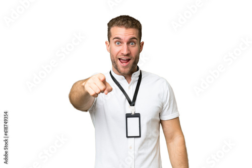 Young caucasian man with ID card isolated on green chroma background surprised and pointing front