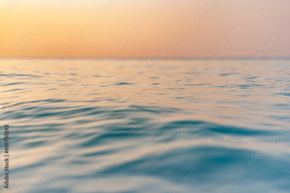 Obraz premium Sea wave closeup, low angle view, sunrise sunset sunlight. Idyllic Earth day seascape. Calm waves, golden orange sky horizon. Tranquil graphic illustration background. Minimal inspire ocean wallpaper