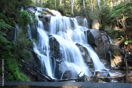 a waterfall flowing down a small waterfall into the ocean under a bridge