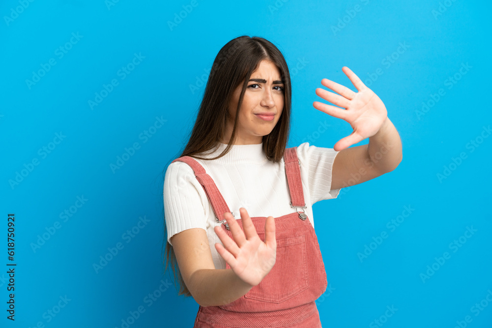 Fototapeta premium Young caucasian woman isolated on blue background nervous stretching hands to the front