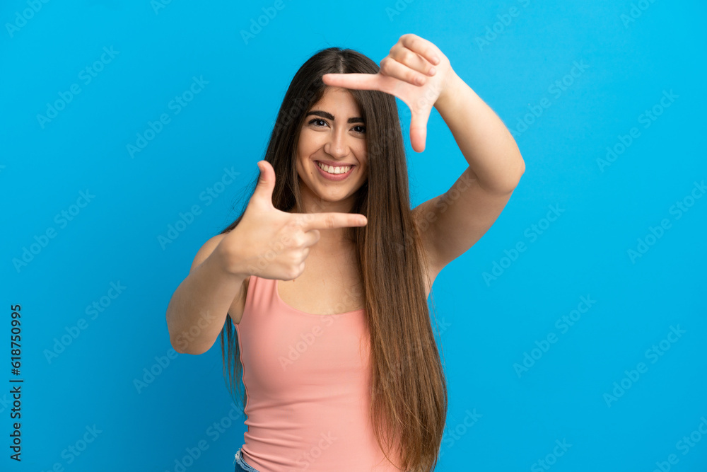 Young caucasian woman isolated on blue background focusing face. Framing symbol