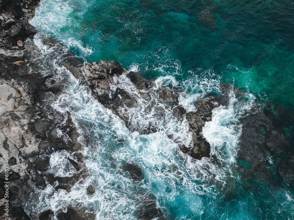 Fototapeta premium waves hitting rocks and cliffs in the sea, viewed from above